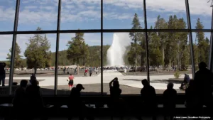 Visitors watch an eruption of Old Faithful from the open Visitor Center.