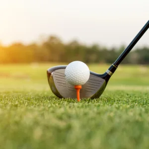 Golf club and ball in grass with sunlight. Close up at golf club and golf ball.