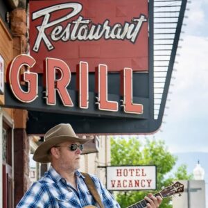 Musician, Aaron Walker with his guitar outside the Irma Hotel.