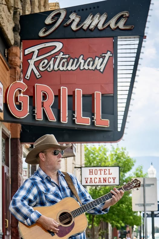 Musician, Aaron Walker with his guitar outside the Irma Hotel.